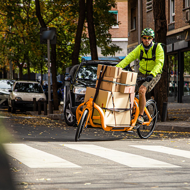 Parcel delivery man turns into a street with his delivery bike